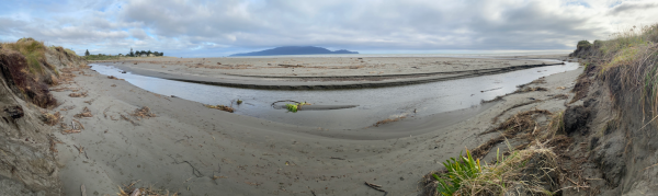 View of Waimeha Stream’s position on Waikanae Beach, seen from the dune near Field Way and facing west toward the sea, with Kāpiti Island visible on the horizon.