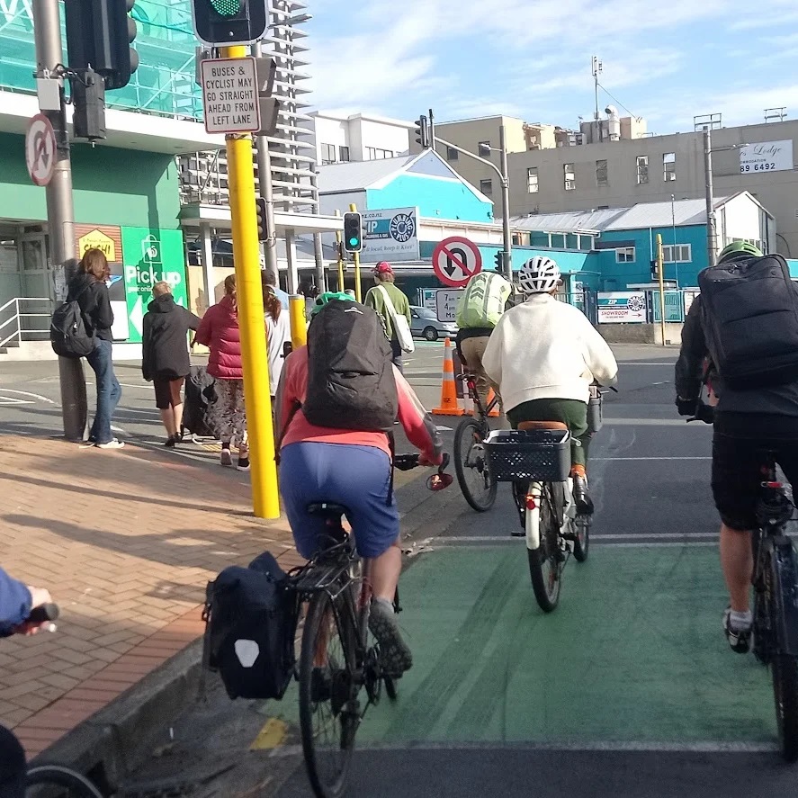 Several cyclists in the bike zone at traffic lights, waiting to go